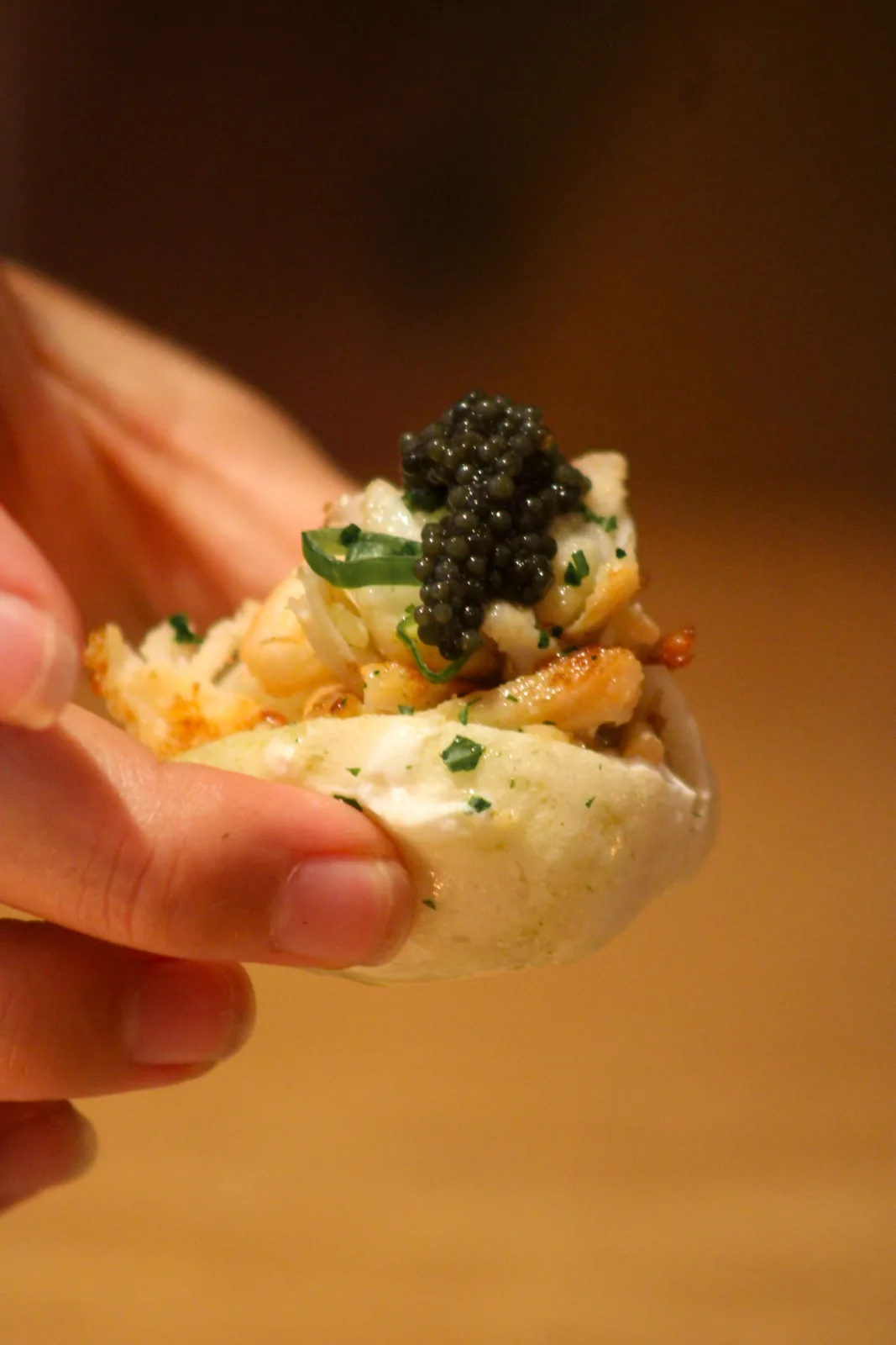 A finished gourmet bite held up for serving