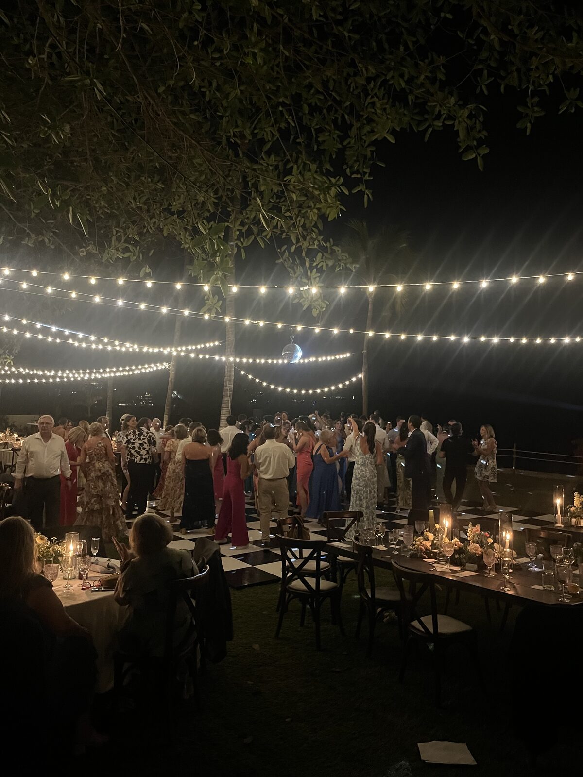 Wedding reception guests dancing under string lights